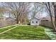 Green backyard with well-maintained grass, a fire pit, a small outbuilding, and mature trees at 611 Tecumseh St, Indianapolis, IN 46201