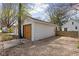 A white garage with a brown door and gravel driveway is next to a well-maintained green lawn at 611 Tecumseh St, Indianapolis, IN 46201