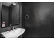 Stylish powder room featuring dark walls, a pedestal sink, and modern fixtures at 611 Tecumseh St, Indianapolis, IN 46201