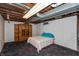 Unfinished basement with wooden support beams, a cabinet, and bed, offering storage and customization potential at 614 Debra Ln, Indianapolis, IN 46217