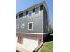 Townhome exterior showcasing siding and brick combination, with a view of the garage doors at 6157 Winthrop Ave, Indianapolis, IN 46220