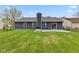 Large backyard with lush green grass, a stone patio, and a chimney on the back of the home at 6159 Connie Ct, Indianapolis, IN 46237