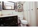 Bathroom with dark wood vanity, framed mirror, shower with curtain, and decorative wall art at 6232 Buck Trail Rd, Indianapolis, IN 46237