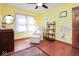 Bright bedroom with hardwood floors, light-yellow walls, ceiling fan, and wall decorations at 6232 Buck Trail Rd, Indianapolis, IN 46237