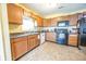 Functional kitchen featuring black appliances, wooden cabinetry, and easy-to-clean tile floors at 6376 Matcumbe Way, Plainfield, IN 46168