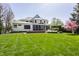 View of backyard with hot tub, screen porch, patio with firepit, outdoor furniture, and manicured landscaping at 7602 N Pennsylvania St, Indianapolis, IN 46240