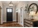 Well-lit entryway with a dark wooden door, decorative mirror, and stylish console table with a lamp at 7602 N Pennsylvania St, Indianapolis, IN 46240