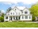 Elegant white modern farmhouse with manicured lawn, covered front porch, and black framed windows at 7602 N Pennsylvania St, Indianapolis, IN 46240