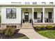 Charming front porch with black door, potted plants, and rocking chairs at 7602 N Pennsylvania St, Indianapolis, IN 46240