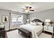 Well-lit bedroom with neutral colors, carpeted floors, a ceiling fan, and a large window at 7618 Ballyshannon St, Indianapolis, IN 46217