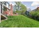 Spacious backyard with lush green lawn, mature trees, landscaping, and a red brick patio at 775 W Hawthorne St, Zionsville, IN 46077
