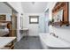Bright bathroom featuring a soaking tub, brass fixtures, and unique vanity with gray tiled floor at 775 W Hawthorne St, Zionsville, IN 46077