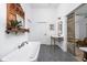 Bright bathroom featuring a soaking tub, brass fixtures, and unique vanity with gray tiled floor at 775 W Hawthorne St, Zionsville, IN 46077