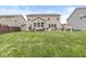 Large backyard featuring a stone patio, lush lawn, and outdoor dining area with a stone fireplace at 7829 Hedgehop Dr, Zionsville, IN 46077
