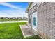 Brick home featuring a backyard patio and lawn overlooking a tranquil pond with neighborhood views at 793 Shepherds Way, Greenwood, IN 46143