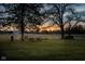 Spacious backyard picnic area featuring a wooden picnic table set against a tranquil field at sunset at 8551 E 300 S, Zionsville, IN 46077