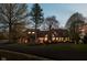 Well-lit home exterior showcasing brick facade, large windows, manicured landscaping, and welcoming entrance at twilight at 8551 E 300 S, Zionsville, IN 46077