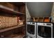 Functional laundry room with washer, dryer, shelving, baskets and stylish wallpaper, blending utility with aesthetic appeal at 8551 E 300 S, Zionsville, IN 46077