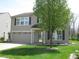 Two-story home featuring neutral siding, dark shutters, an attached garage, and a green front yard at 9045 Stones Bluff Pl, Indianapolis, IN 46113