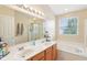 Bright bathroom featuring double sinks, a large mirror, separate shower, and a soaking tub with a window at 9099 Merrill Ct, Fishers, IN 46038