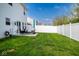Spacious backyard with a well-manicured lawn, white fence, and patio seating area at 10538 Rose Mill Dr, Lawrence, IN 46235