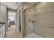 Spa-like bathroom with glass-enclosed shower, beige tiles, and view into an adjacent bedroom at 10805 Soda Creek Ct, Indianapolis, IN 46239