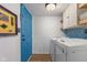 Well-equipped laundry room with washer, dryer, cabinets, and decorative blue tiling at 12449 Huntington Dr, Indianapolis, IN 46229