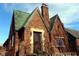 Quaint red brick home featuring a chimney, green roof, and decorative iron entry door at 3208 Brookside Pkwy N Dr, Indianapolis, IN 46218