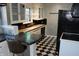 Functional kitchen featuring a breakfast bar, white cabinetry, black countertops, and black and white tiled floors at 3208 Brookside Pkwy N Dr, Indianapolis, IN 46218