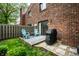 Charming backyard features a brick house, a small patio with teal chairs, and a manicured lawn with stepping stones at 354 E Arch St, Indianapolis, IN 46202