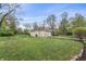 Spacious backyard featuring lush lawn, mature trees, and a detached garage at 3818 Kessler Boulevard East Dr, Indianapolis, IN 46220