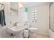 Bright bathroom featuring a pedestal sink, toilet, and a window at 3818 Kessler Boulevard East Dr, Indianapolis, IN 46220