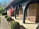 Close-up of a cozy front porch with arched detailing, flower beds, and an American flag at 3920 Pigeon Creek Ln, Indianapolis, IN 46234