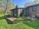 Sunroom exterior with brick patio, wooden bench, well-maintained lawn, and mature trees at 3920 Pigeon Creek Ln, Indianapolis, IN 46234