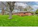 Spacious backyard with a well-maintained lawn, mature trees, and a charming deck attached to a brick house at 4464 Chatham Dr, Brownsburg, IN 46112