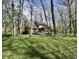 Spacious backyard with a deck, screened porch, mature trees, and lush greenery at 5205 Mosswood Ct, Indianapolis, IN 46254