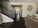 Modern entryway with dark wood floors, black metal railing staircase, and view into decorated hallway at 5529 W Turnbuckle Pl, McCordsville, IN 46055