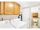 This laundry room features a modern white washer and dryer set with wood cabinets at 5937 Terrytown Pkwy, Indianapolis, IN 46254