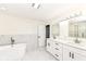 Elegant bathroom with a soaking tub, double vanity, white cabinetry, and marble tile, creating a spa-like retreat at 6507 Tram Ct, Indianapolis, IN 46260