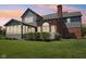 Twilight view of backyard featuring gray siding, brick chimney, arch window and inviting screened-in porch with green lawn at 7323 Elm Ridge Dr, Indianapolis, IN 46236