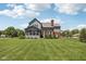 View of expansive backyard with gray siding, brick chimney, arch window, inviting screened-in porch and basketball hoop at 7323 Elm Ridge Dr, Indianapolis, IN 46236