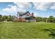 Expansive backyard showcasing a well-maintained lawn, mature trees, and the home's charming architecture under a bright sky at 7323 Elm Ridge Dr, Indianapolis, IN 46236