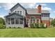 Image of home's backyard, displaying the gray siding, brick chimney, arch window, and an inviting screened-in porch at 7323 Elm Ridge Dr, Indianapolis, IN 46236