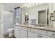 Bathroom showcasing double sinks, granite countertops, white cabinets, and natural light from the window at 7323 Elm Ridge Dr, Indianapolis, IN 46236