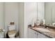 Bright bathroom featuring toilet with brown seat cover, vanity with granite countertop, undermount sink, and white cabinets at 7323 Elm Ridge Dr, Indianapolis, IN 46236