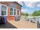 Outdoor deck showcasing a dining set and barbecue grill with brick exterior and lush green surroundings at 7323 Elm Ridge Dr, Indianapolis, IN 46236