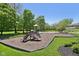Community playground featuring a slide and swing set with wood chip base and green lawn under clear blue sky at 7323 Elm Ridge Dr, Indianapolis, IN 46236