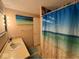 Well-maintained bathroom with a shower featuring a beach-themed curtain, vanity sink, and serene ambiance at 7334 E 14Th St, Indianapolis, IN 46219