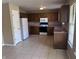 Well-lit kitchen featuring tile flooring, wooden cabinetry, and modern appliances at 7450 Cobblestone W Dr, Indianapolis, IN 46236