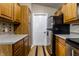 Galley kitchen with stainless steel refrigerator and wooden cabinets leading to a white door at 8911 Hunters Creek Dr # 311, Indianapolis, IN 46227